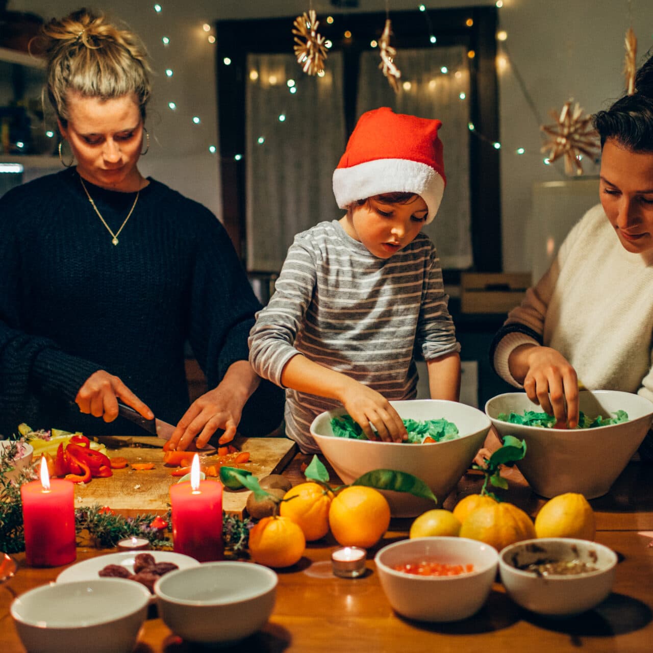 Tips för en hållbar jul. En familj med ett barn i tomtemössa lagar julmat.