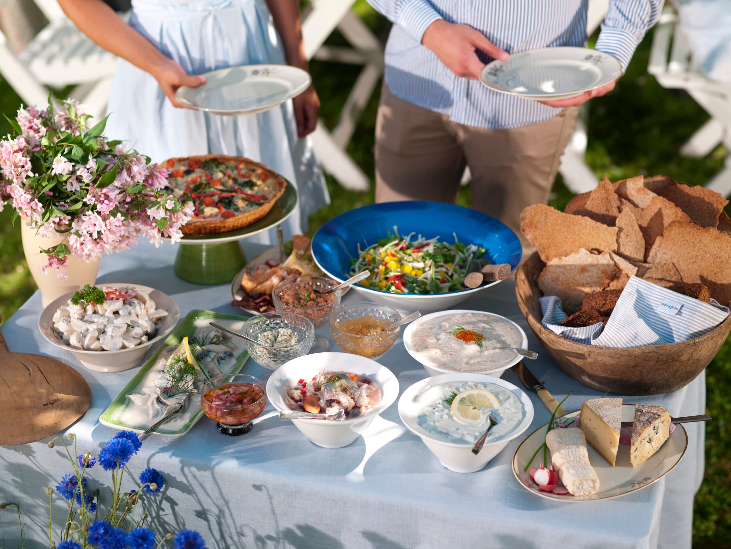 njutning, tradition, två personer, lycka, fritidskläder, tallrik, samhörighet, ung vuxen man, ung vuxen kvinna, vy ovanifrån, buffé, sallad, grönsak, dagtid, stående, sommar, ost, 20-24 år, optimism, utomhus, paj, sill, knäckebröd, skål, Sverige, frukt och grönsaker, fest, bord, sommarmat, svensk tradition.