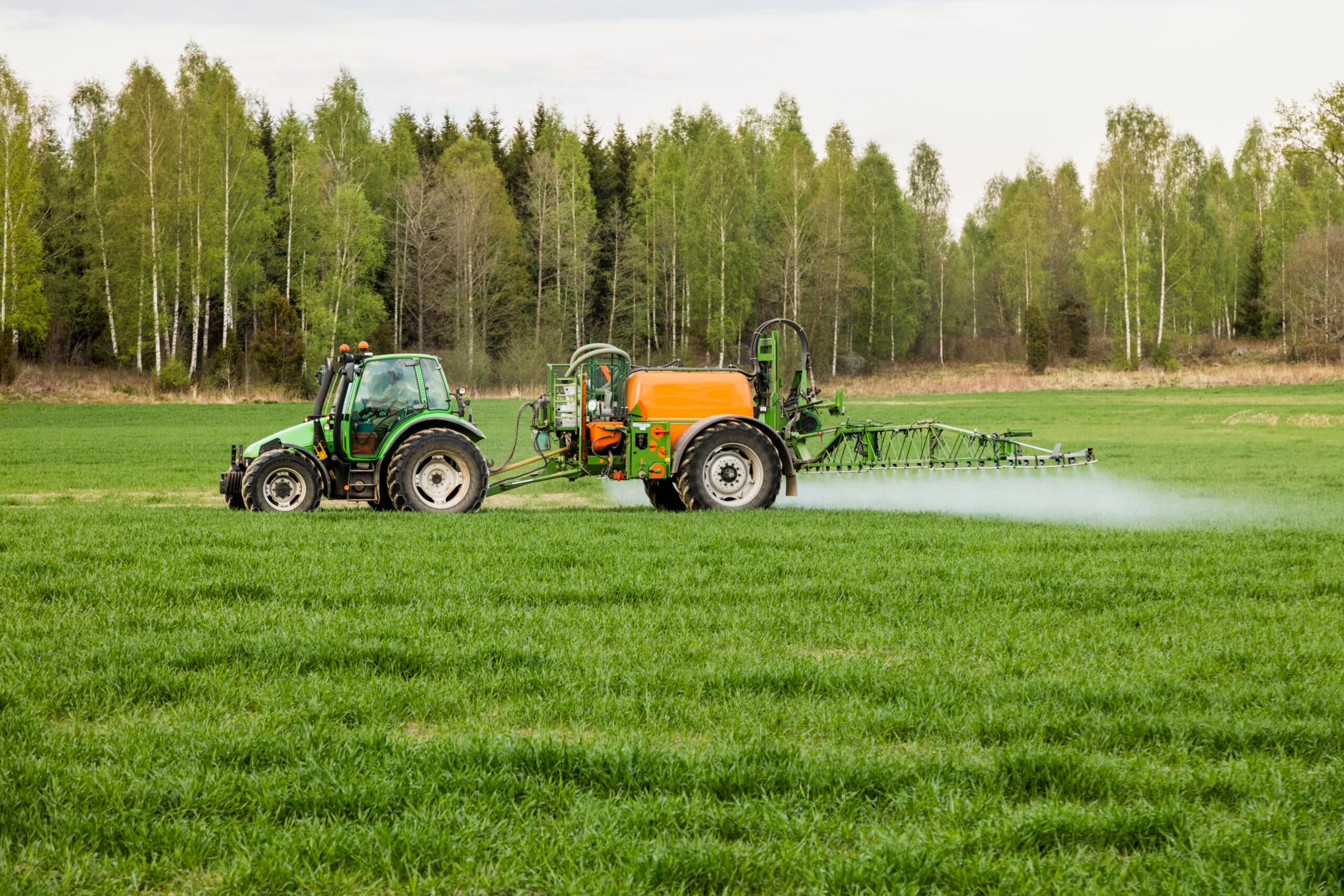 En traktor besprutar ett fält med bekämpningsmedel med PFAS någonstans i Sverige